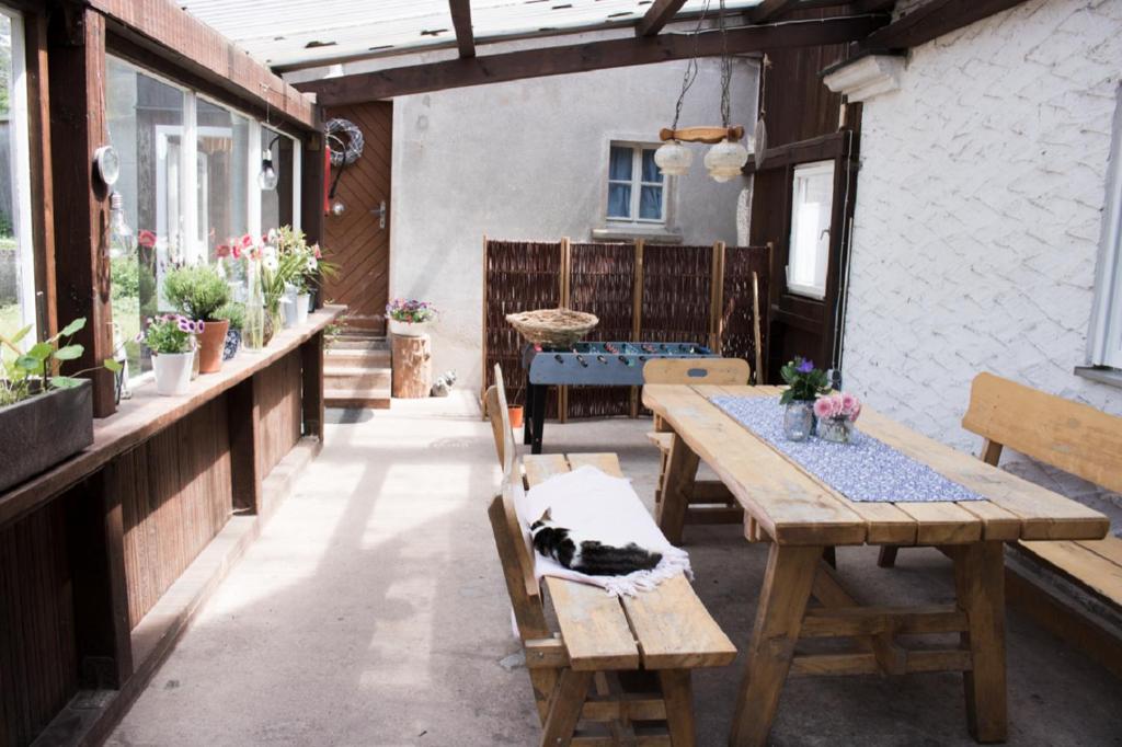 een patio met een houten tafel en stoelen met een kat erop bij Ferienwohnung Schwabenhof in Leutershausen