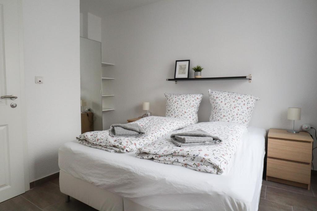 a bedroom with a bed with white sheets and pillows at Apartments am Lindengraben in Emden