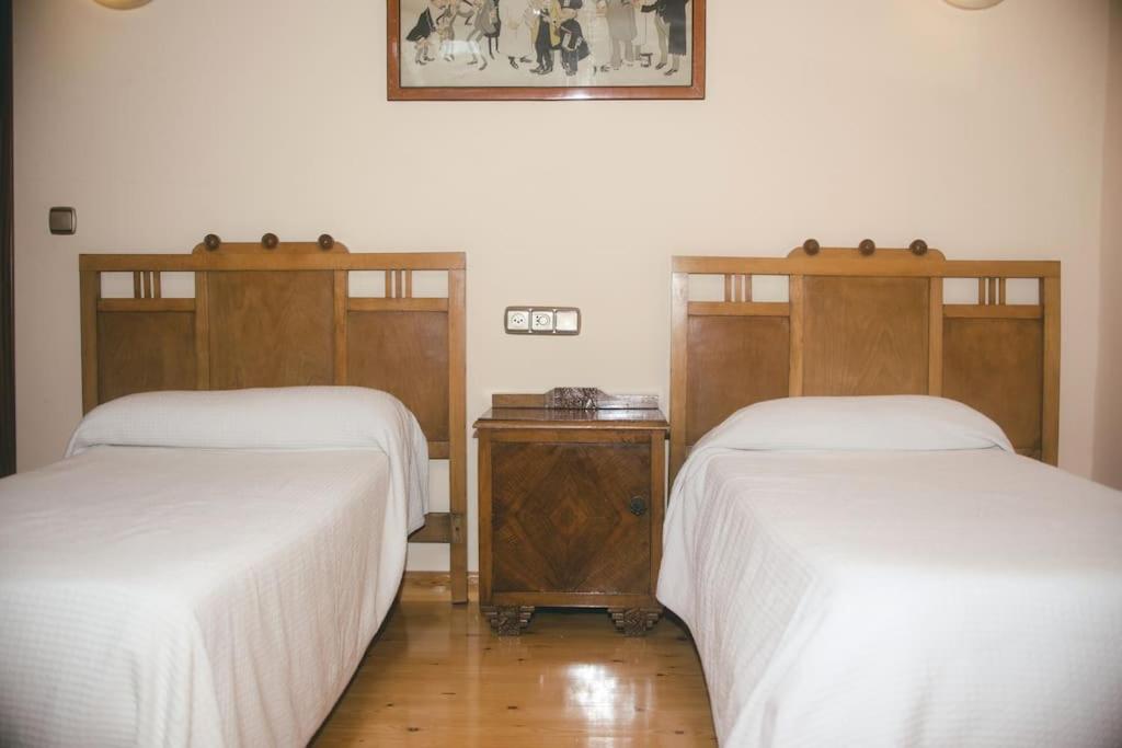 Las Caldas de Boñar Casa alquiler completo في بونيار: سريرين في غرفة ذات أغطية بيضاء