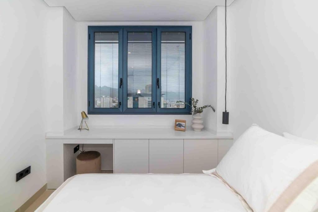 a white bedroom with a bed and a window at NR Urban Torre 2 in Santa Cruz de Tenerife