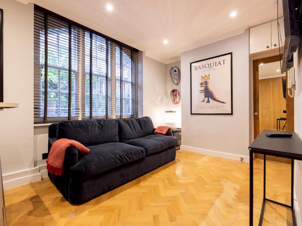 a living room with a black couch and some windows at Pass the Keys Stylish 1 bedroom flat by Kings Road in Chelseag in London