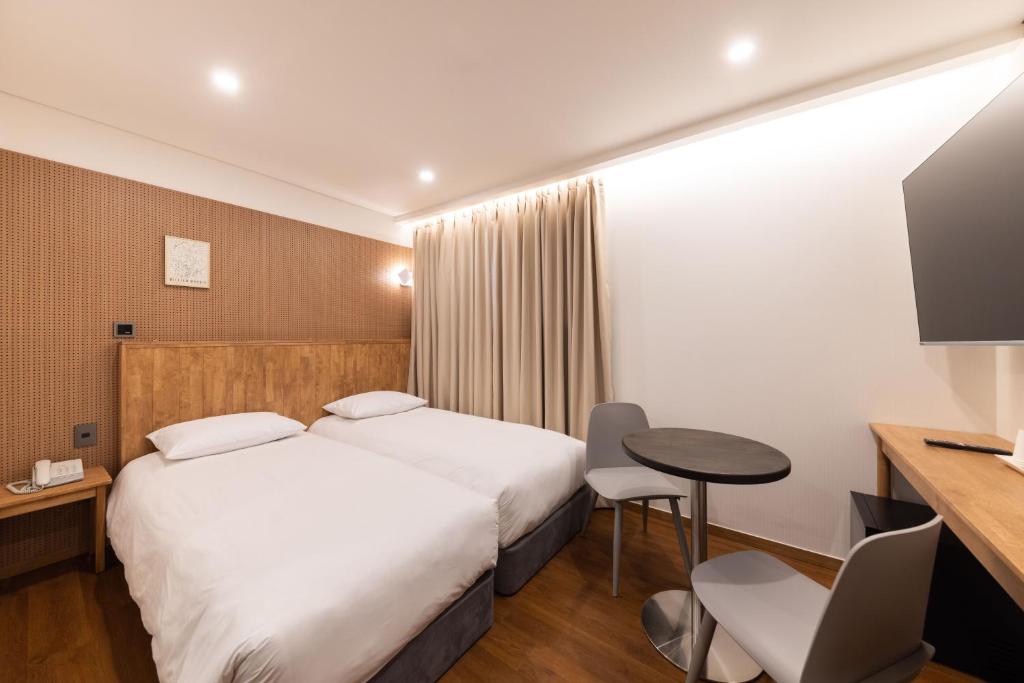 Habitación de hotel con 2 camas y mesa en ARA Hotel, en Seúl