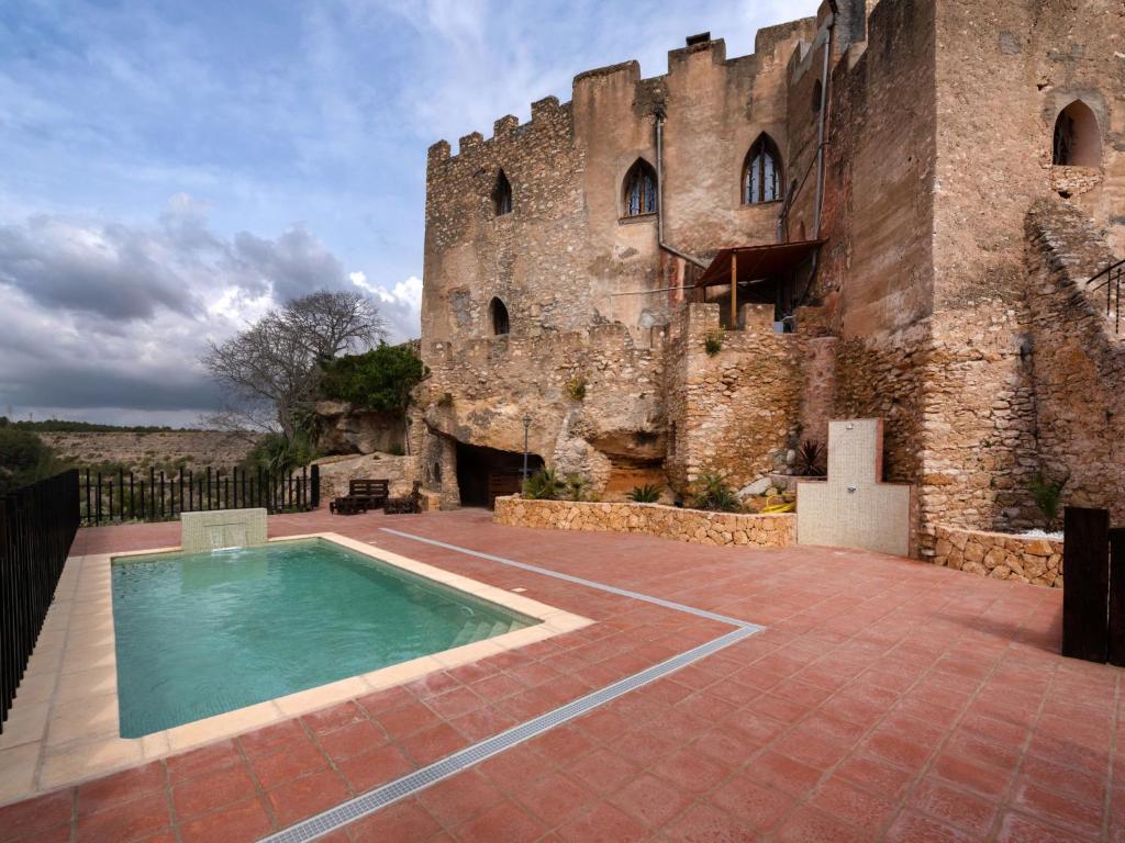 un edificio con piscina frente a un castillo en Holiday Home Mas d'en Tarres by Interhome, en Vespellà