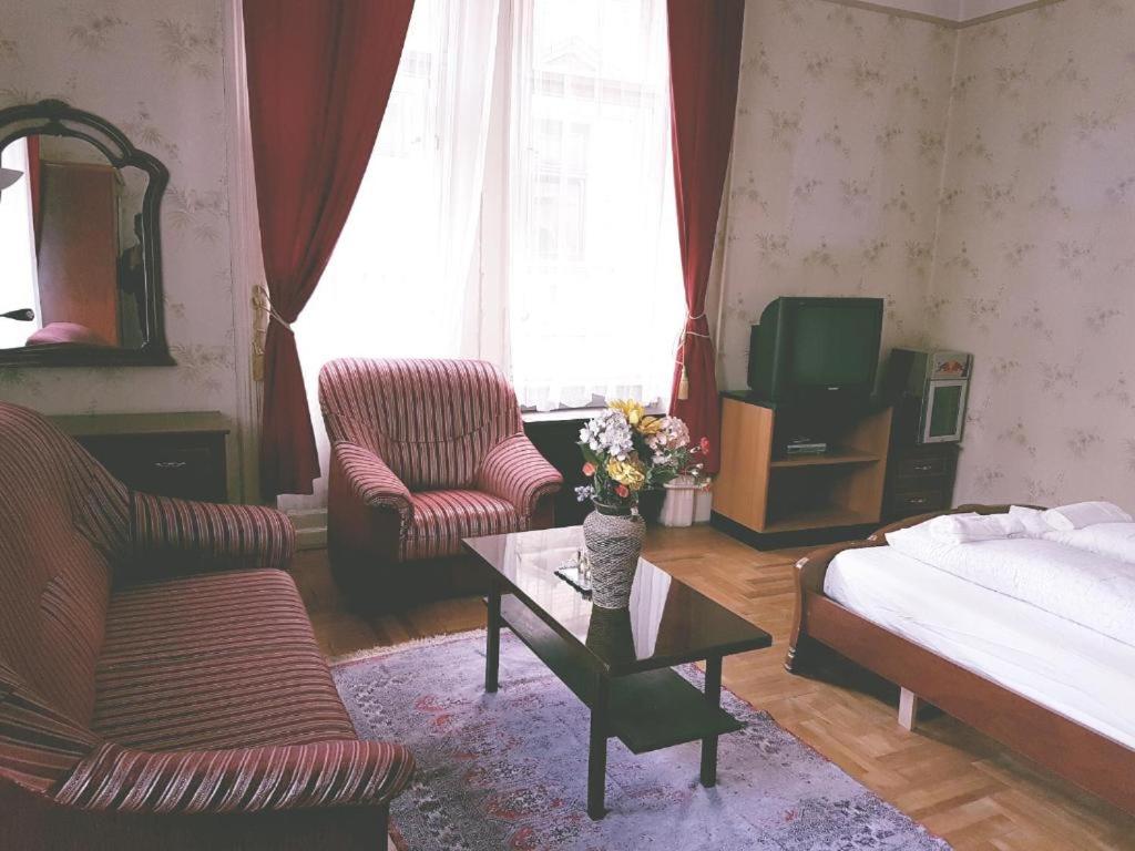 a living room with a bed and two chairs and a table at Retro Rooms in Budapest