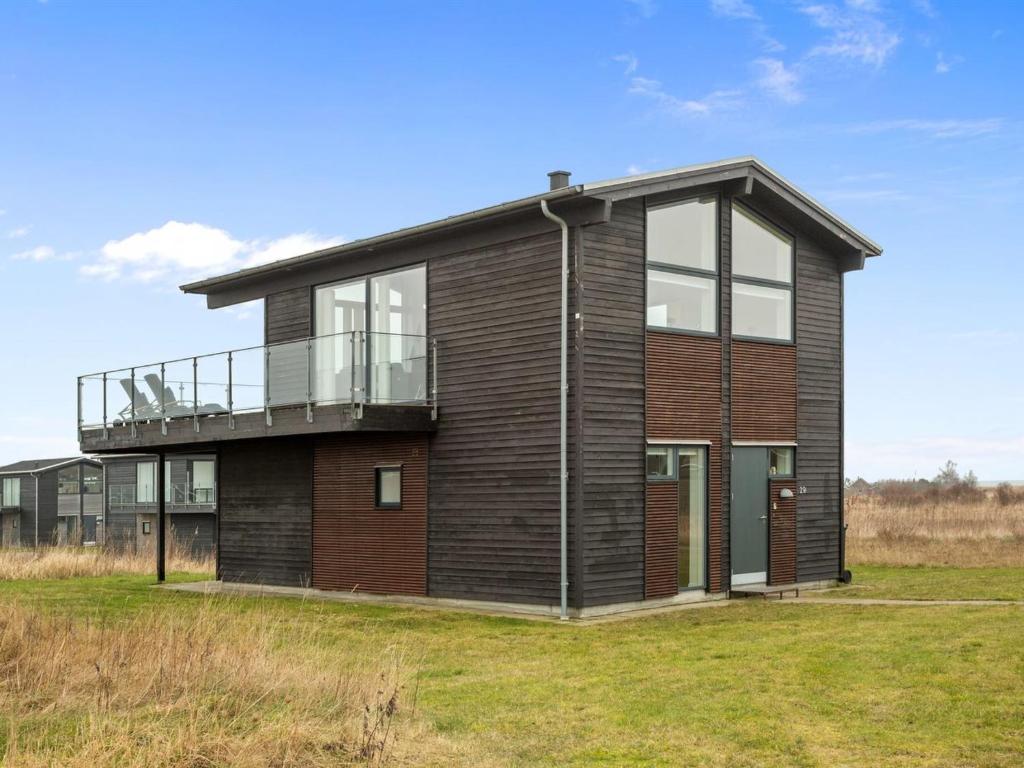 a house with a balcony on top of a field at Holiday Home Gerniot - 500m from the sea in NE Jutland by Interhome in Frederikshavn