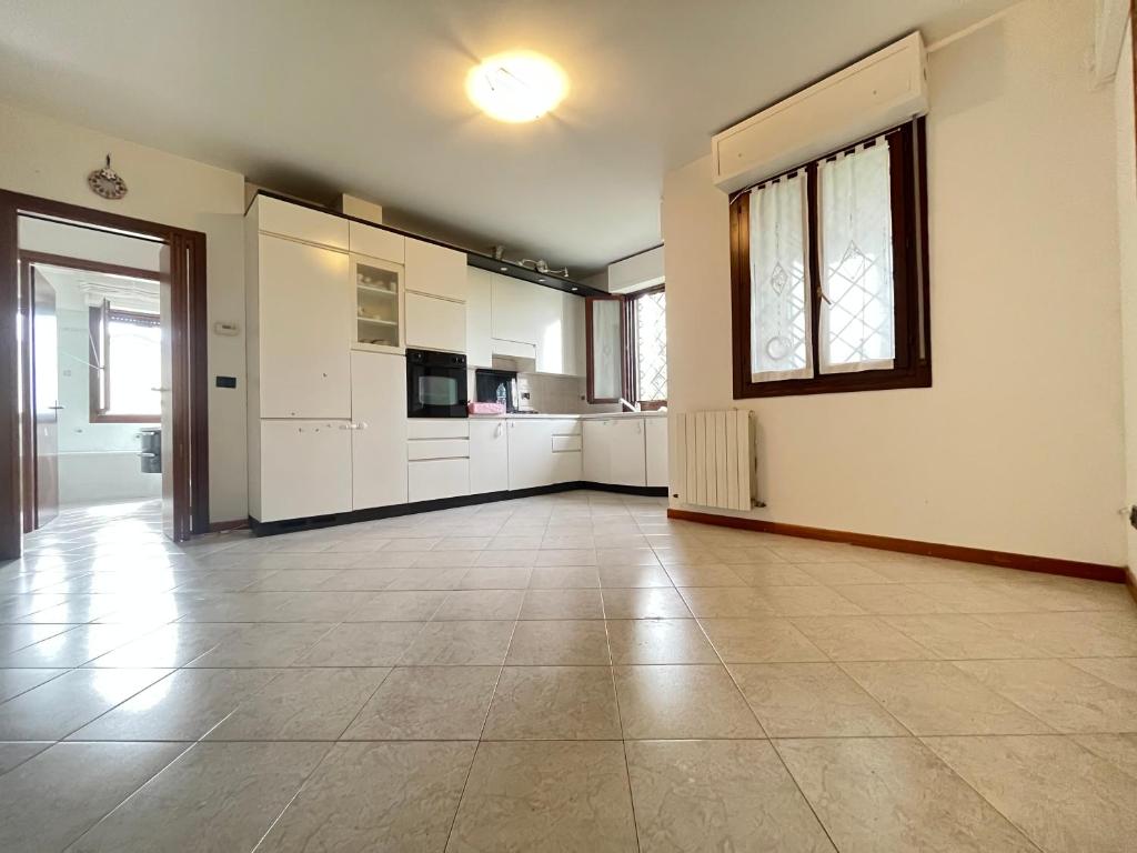 a large kitchen with white cabinets and a tile floor at Gramsci suite home in Casa la Luna