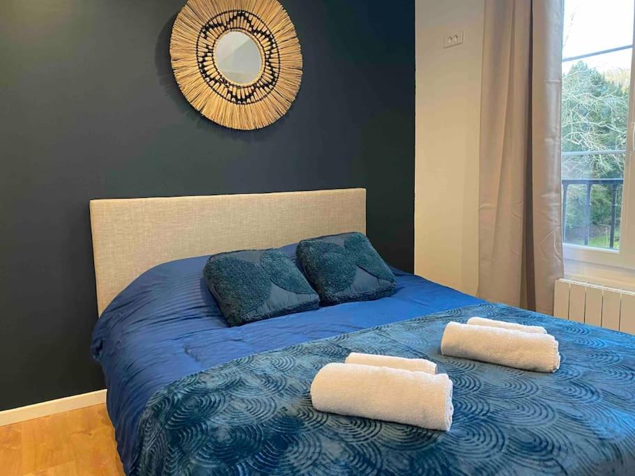 een blauw bed met 2 kussens en een spiegel bij 02 Appart cozy à 5min de Fontainebleau in Bourron-Marlotte