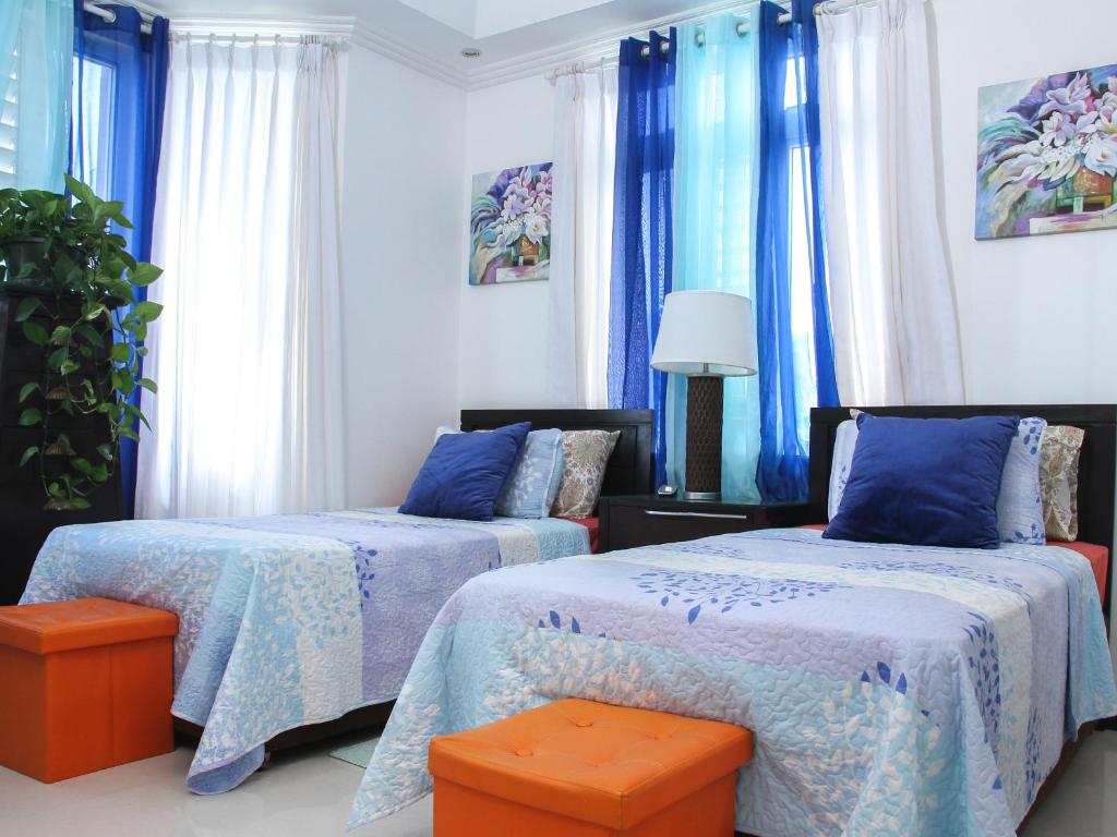 duas camas num quarto com cortinas azuis em Zenbreak Bliss Twin Bedroom em Bridgetown