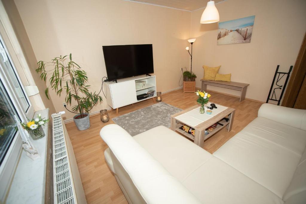sala de estar con sofá blanco y TV de pantalla plana en Ferienwohnung in Bitterfeld-Wolfen, en Große Mühle