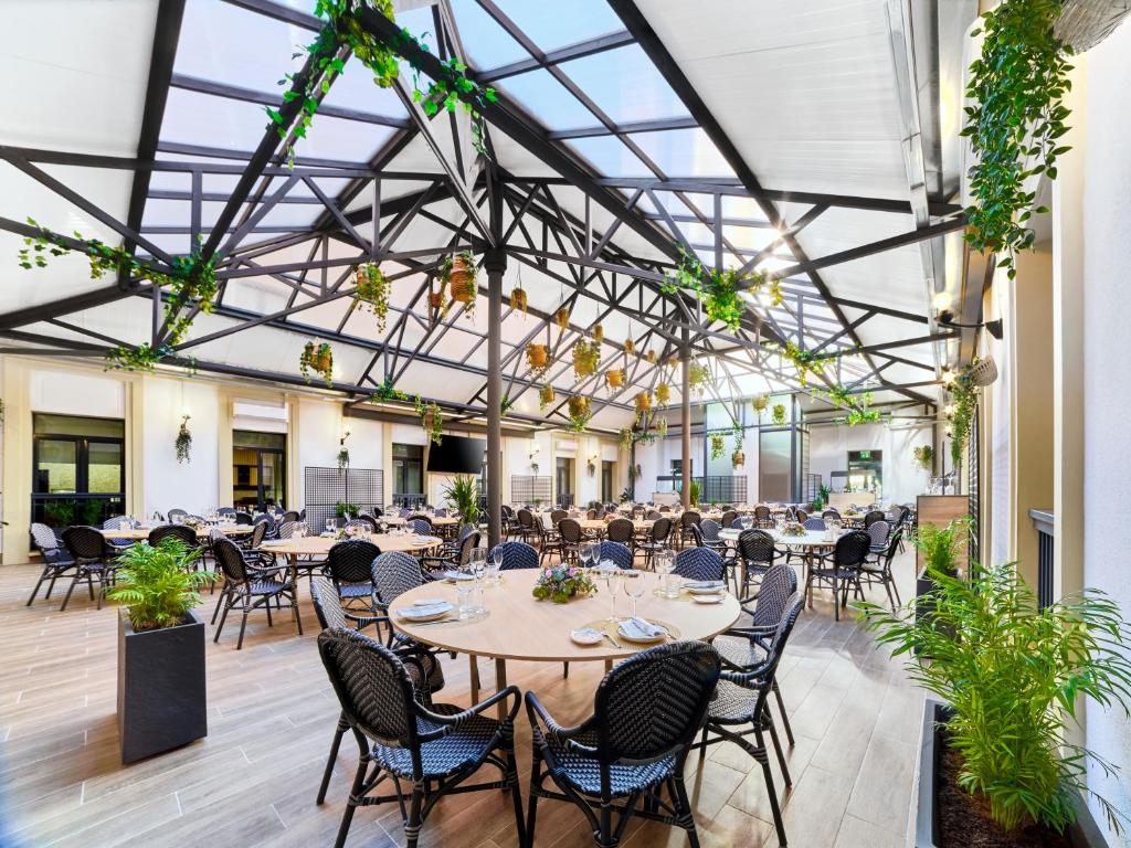 a banquet hall with tables and chairs and plants at Sercotel AB Arganda in Arganda del Rey