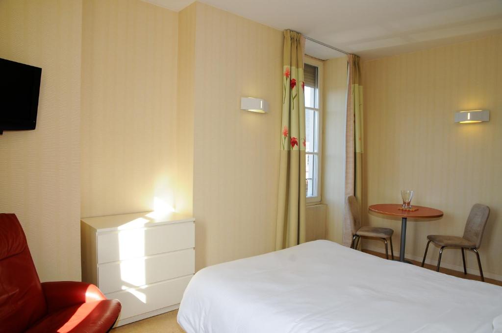 a bedroom with a bed and a table and a chair at Hotels &amp; Résidences - Les Thermes in Luxeuil-les-Bains