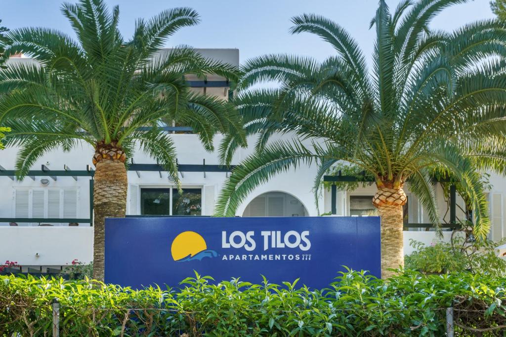una señal frente a un edificio con palmeras en Apartamentos Los Tilos en Paguera