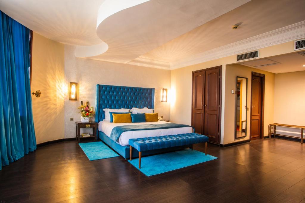 a bedroom with a king sized bed with a blue headboard at Le Zenith Hotel & Spa in Casablanca