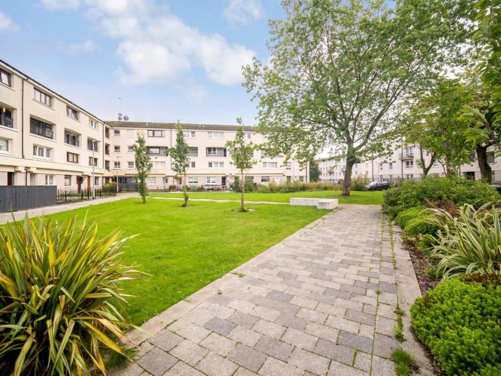 an apartment building with a garden in front of it at Lovely 1-bedroom property with balcony in West end in Glasgow