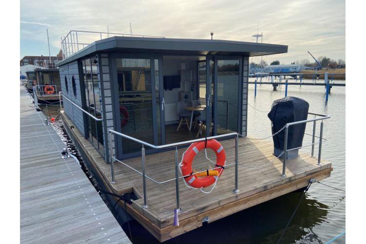 ein kleines Haus auf einer Anlegestelle am Wasser in der Unterkunft Hausboot Fjord Vela mit Biosauna in Barth in Barth