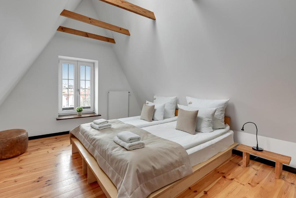 a white bedroom with a large bed with wooden floors at City & Old Town View Rooftop by Downtown Apartments in Gdańsk