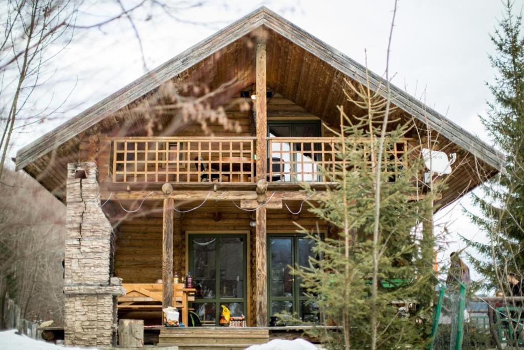 a log cabin with a wrap around porch at Cabana La Panţiru in Văleni-Stînişoara