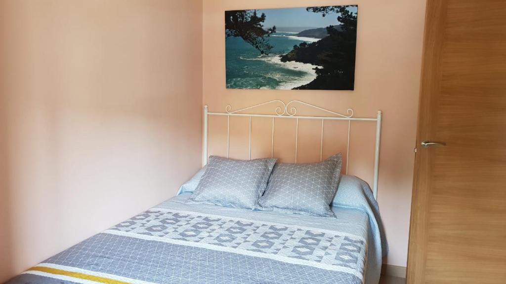 ein Bett in einem Schlafzimmer mit einem Bild an der Wand in der Unterkunft Leutoño in Malpica