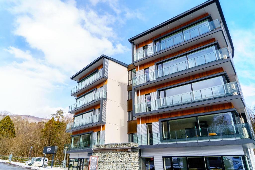 an apartment building with balconies on a street at Mountain Side Hakuba in Hakuba