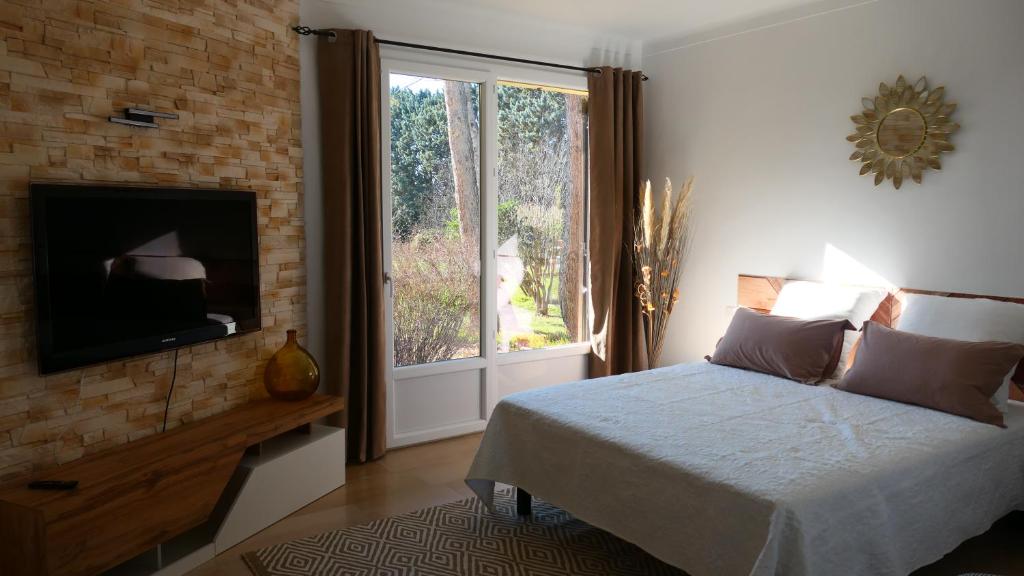 een slaapkamer met een bed, een tv en een raam bij LE PATIO in Sarrians