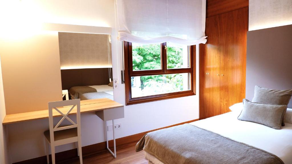 a bedroom with a bed and a desk and a window at Hotel Ocamiño in Durango