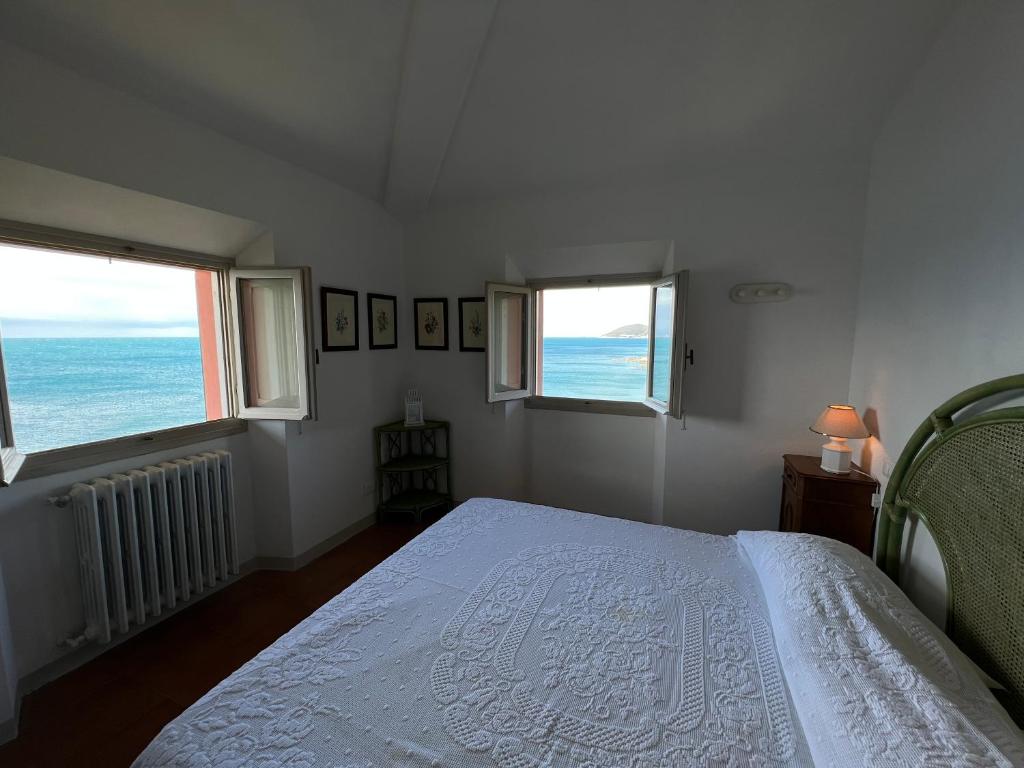 sypialnia z łóżkiem i 2 oknami w obiekcie Appartamenti sul mare Villa il Fortullino w mieście Case Fortullino
