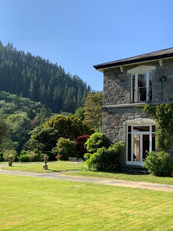 a stone house on a field with a mountain in the background at Riverside apartment in Betws-y-coed