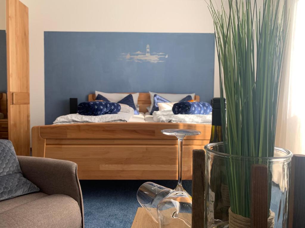 a bedroom with a bed with blue walls and a potted plant at Hotel Meerblick garni in Neuharlingersiel