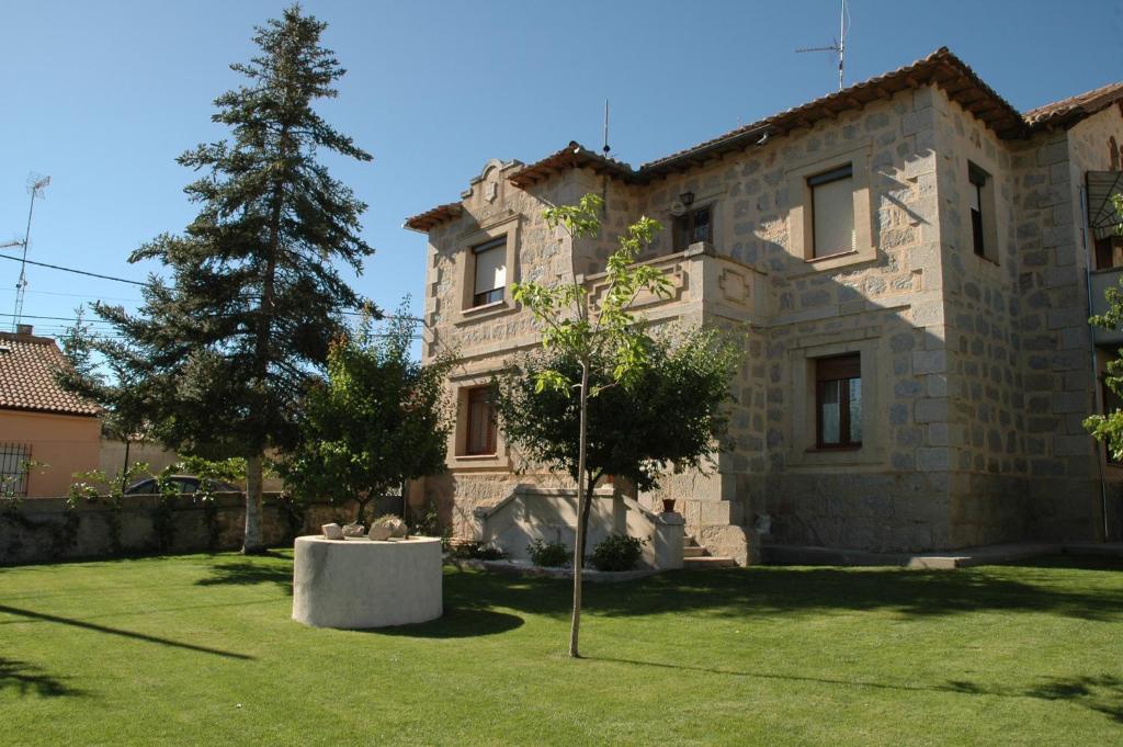 una gran casa de piedra con un árbol en el patio en Casa Rural Reposo de Afanes, en Muñogalindo