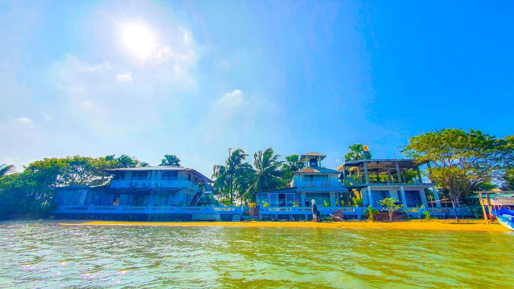 two blue houses on the shore of a body of water at Dinuda Resort in Kalpitiya