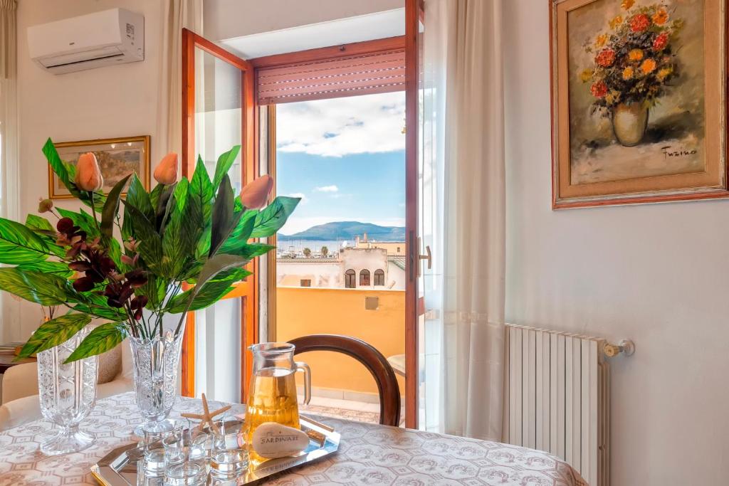 een tafel met een vaas met bloemen en een raam bij SARDINIA RE - Catalogna 62 in Alghero
