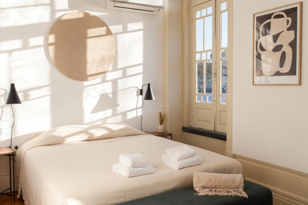 a bedroom with a white bed with towels on it at Alameda Suites - River Guest House in Porto