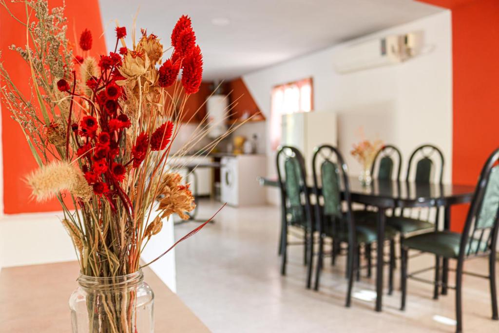 un jarrón lleno de flores rojas sentado en una mesa en Casa El Roble en San Rafael