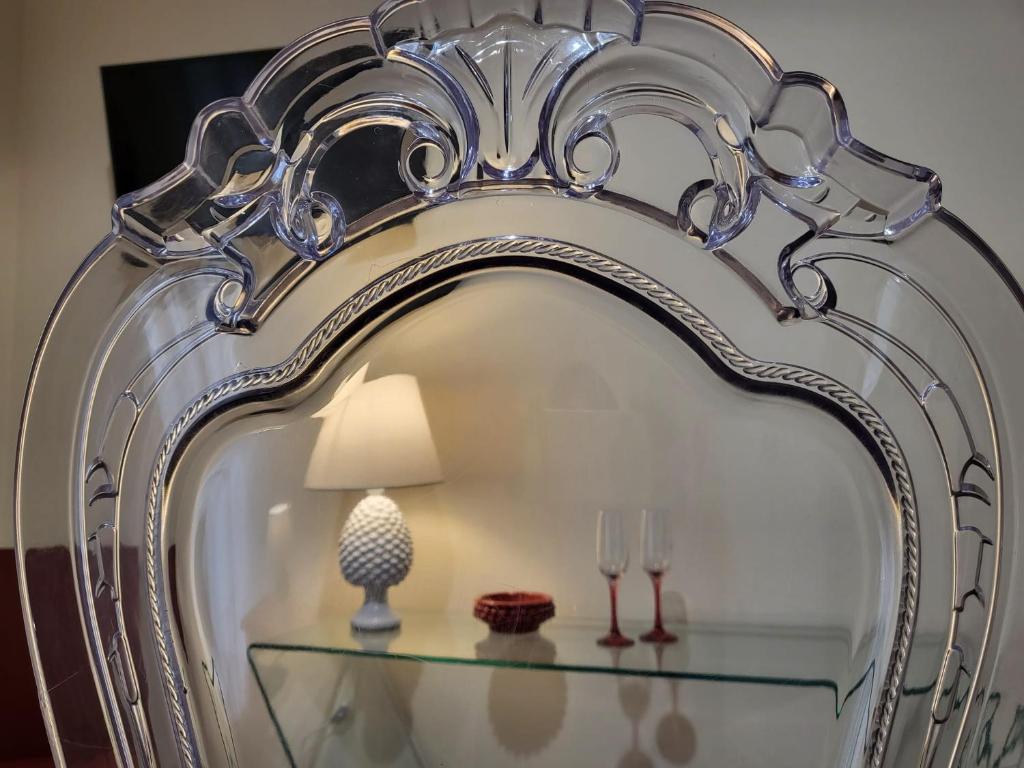 a mirror with a lamp and glasses on a glass table at Atena apartments in Agrigento