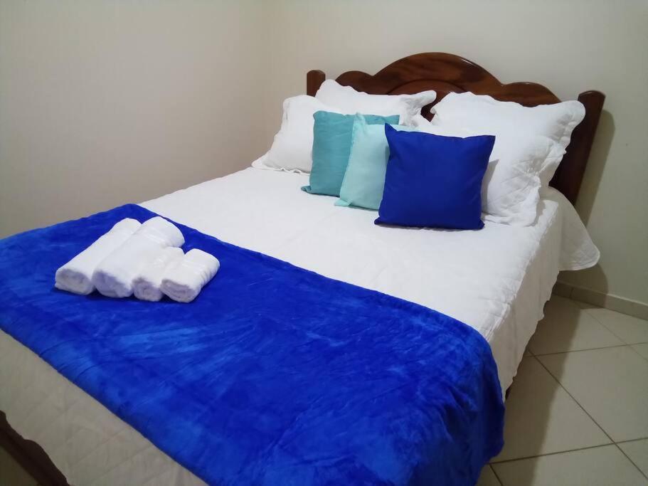 a bed with blue and white pillows on it at LAGOA II SAQUAREMA RJ in Saquarema