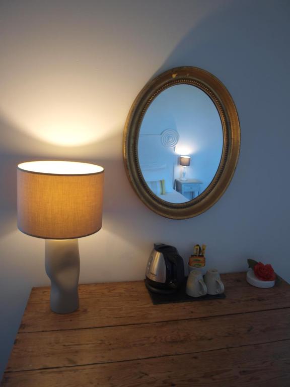 a lamp sitting on a table with a mirror at L&#39;Estanquet Bed and Breakfast pdj offert in Gastes