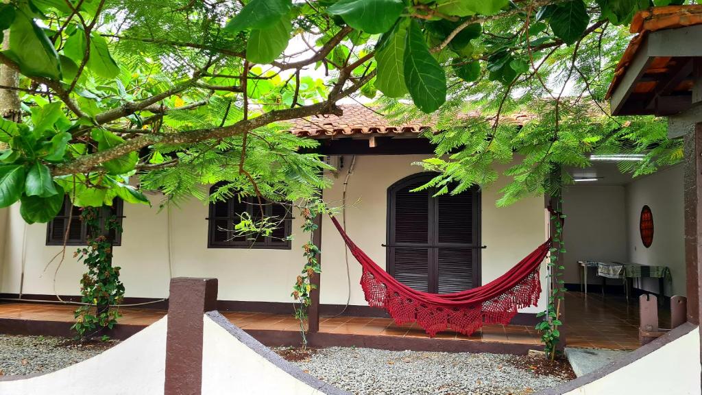 a house with a red hammock in front of it at Casa praia Enseada in São Francisco do Sul