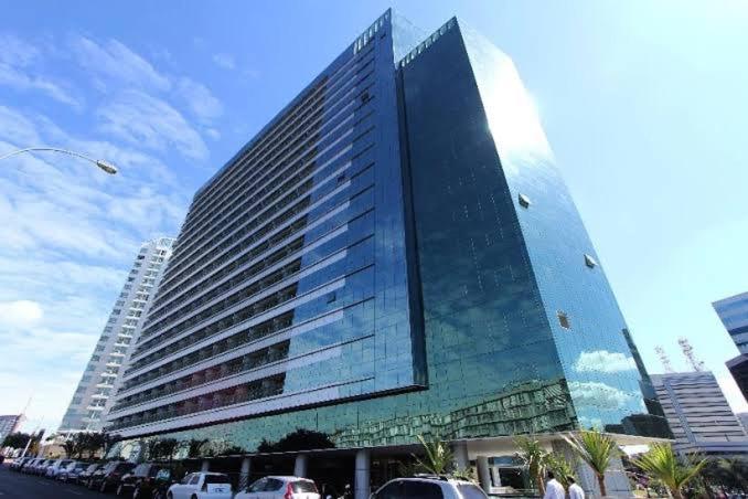 a tall building with cars parked in front of it at Flat Hotel Vision Hplus frente para Esplanada - SEM CAFÉ - Acomodação Particular in Brasilia