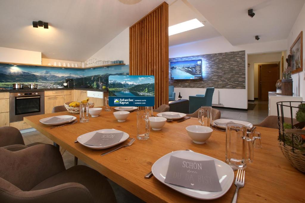 湖畔捷爾的住宿－Alm Appartements ZellamSee，厨房里一张木桌,上面放有盘子和玻璃杯