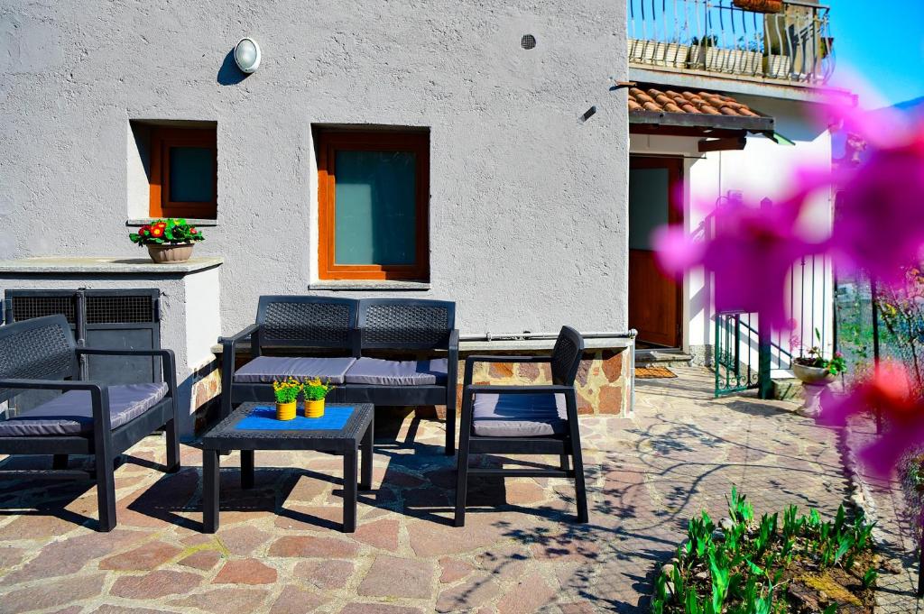 eine Terrasse mit Stühlen, einem Tisch und einem Gebäude in der Unterkunft Quadrifoglio Apartment by Wonderful Italy in Bellagio
