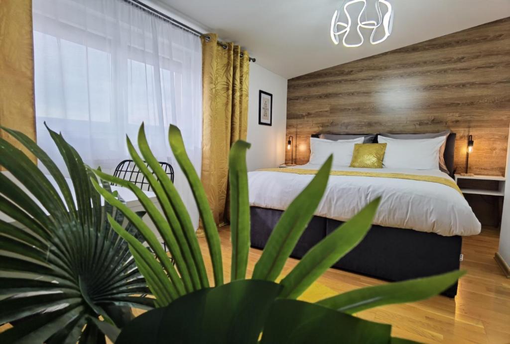 ein Schlafzimmer mit einem großen Bett und einer Pflanze in der Unterkunft Sun Deluxe Apartment in Banja Luka