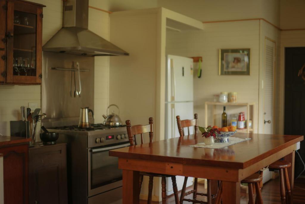 uma cozinha com uma mesa de madeira e um fogão forno superior em Freida - Historic Farmhouse Bellingen em Gleniffer