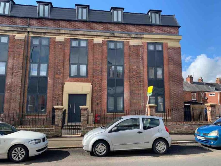 two cars parked in front of a brick building at Newly built 2 bed flat in the heart of Leek in Leek