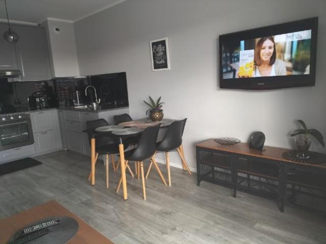 eine Küche mit einem Tisch und Stühlen sowie einen TV an der Wand in der Unterkunft Apartament przy Aquaparku w Redzie in Rumia