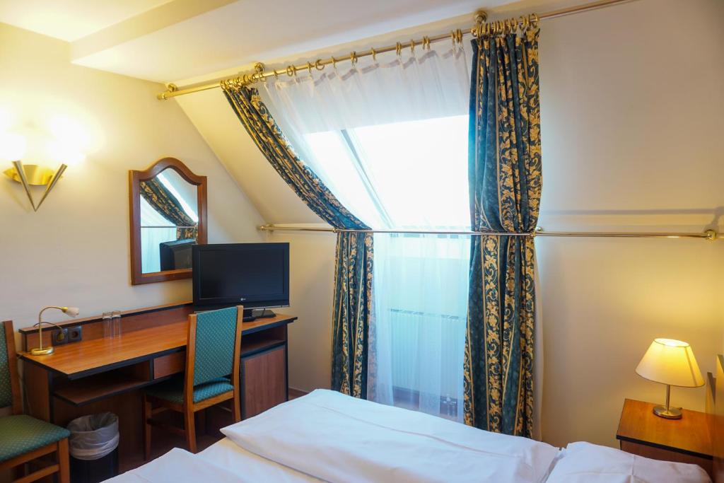 Hotel Deutschmeister في فيينا: غرفة في الفندق بها مكتب وسرير ونافذة