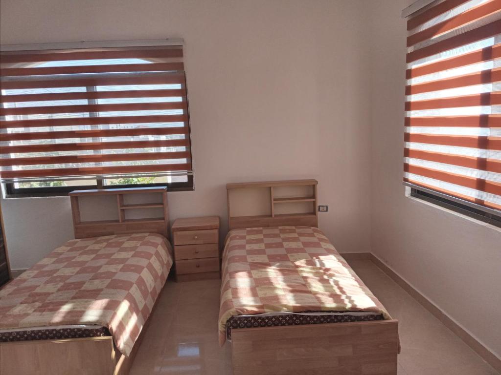 2 camas en una habitación con 2 ventanas en Jarash en Jerash