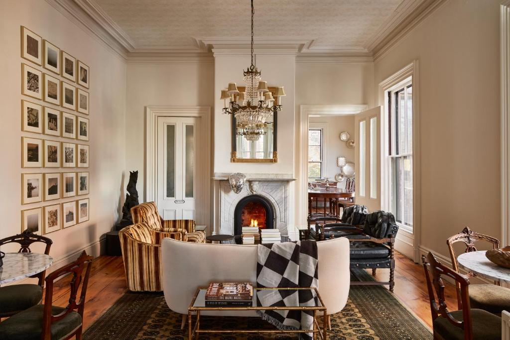 a living room with a fireplace and a table and chairs at Blind Tiger Portland - Carleton Street Guest House in Portland