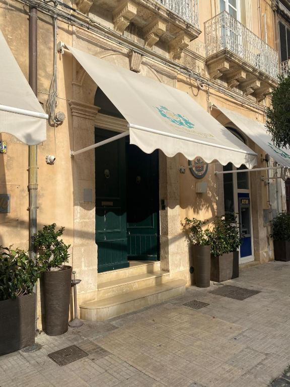 a building with a green door and a white umbrella at Hotel Gran Bretagna Ortigia in Syracuse