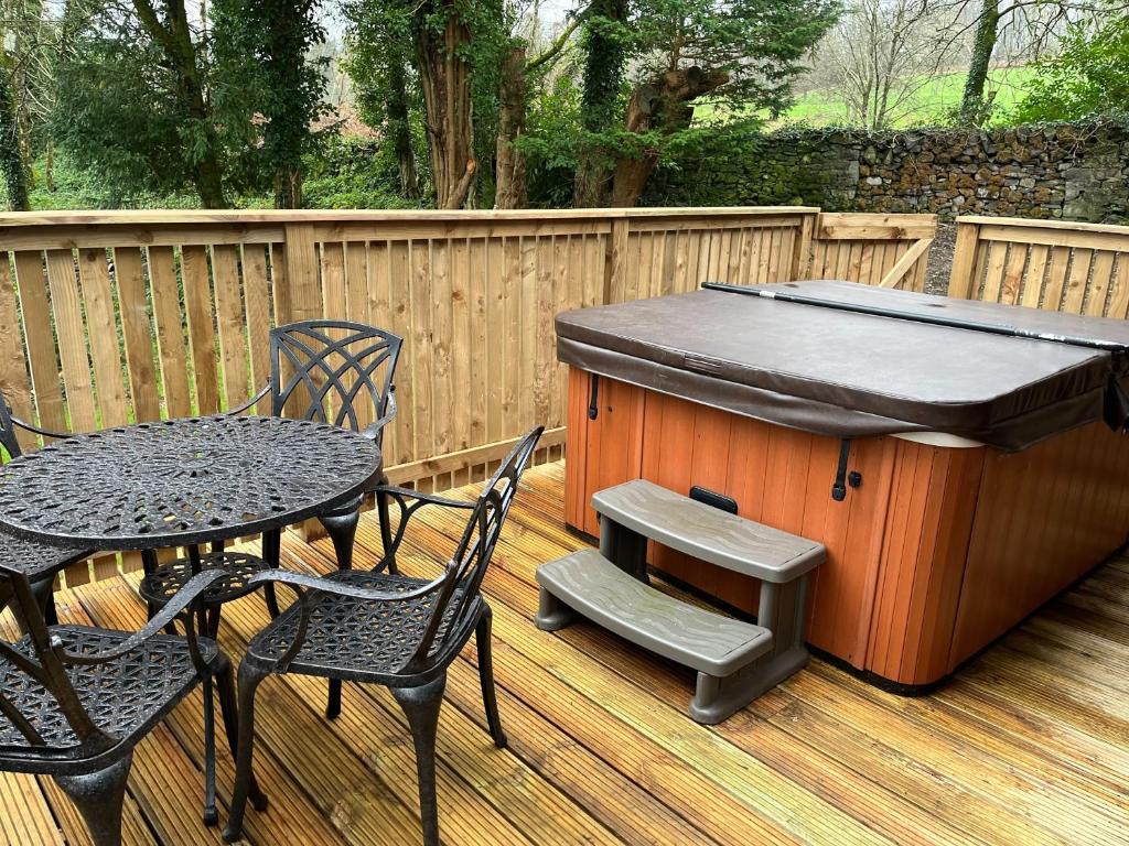 a barbecue grill on a deck with a table and chairs at Birch Lodge 23 with Hot Tub in Newton Stewart