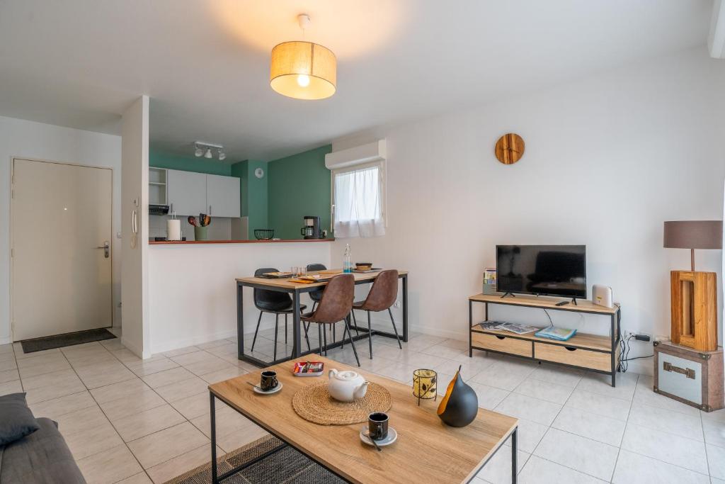 a living room with a table and a kitchen at LaConciergerieJonzac, Appartement Le Carré des Antilles 2 in Jonzac